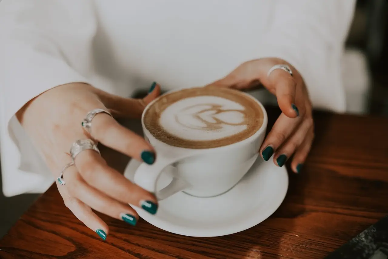 Olive green nails holding a latte